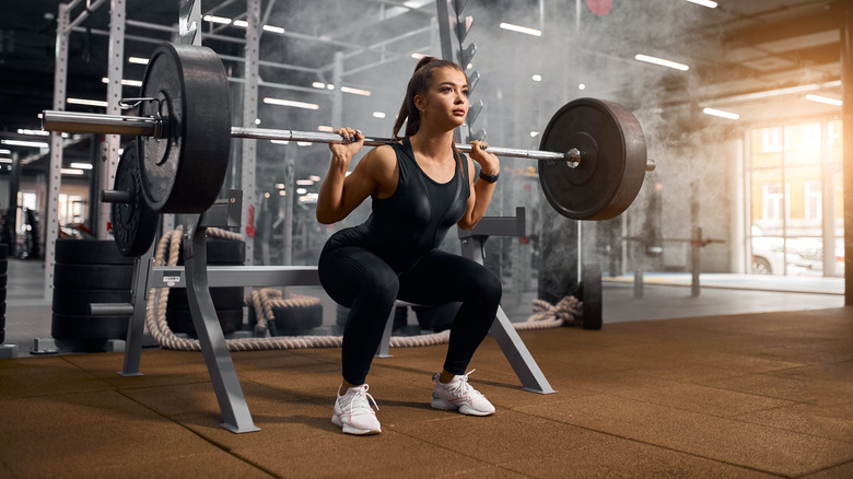 Powerlifter doing prisoner squat with heavy barbell