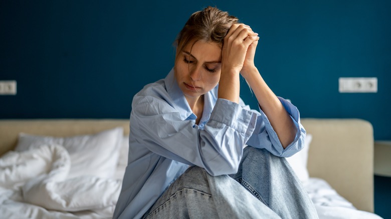 Unhappy woman sitting on bed