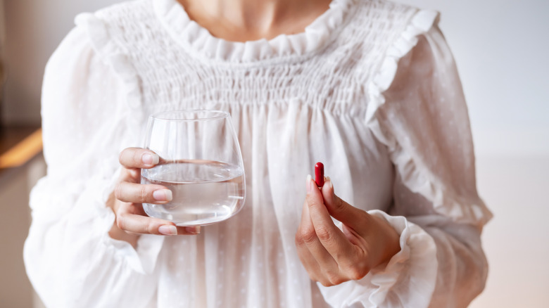 woman holding pill and water