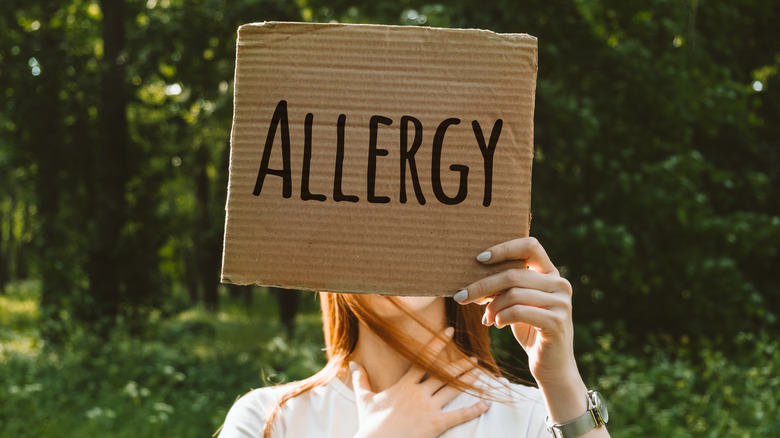 Woman holding a sign that says "allergy"