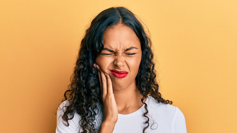 Woman holding her right cheek in discomfort