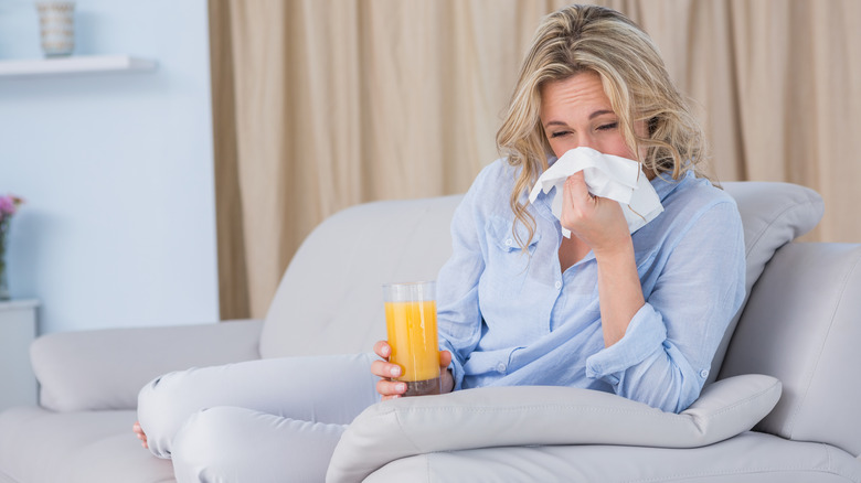 woman blowing nose with orange juice