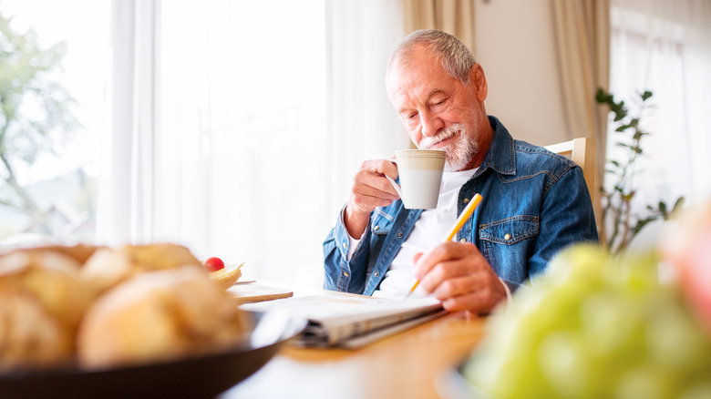 An elderly man does a crossword puzzle