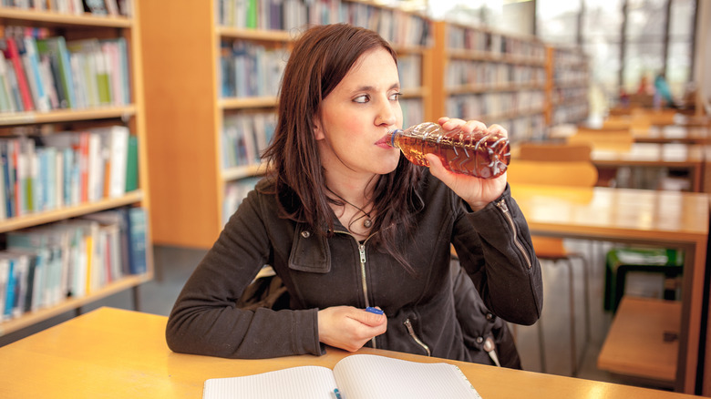 woman drinking iced tea in library
