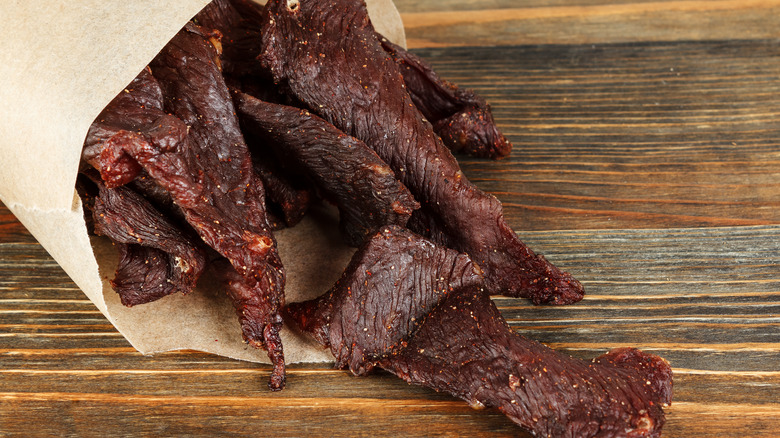 Beef jerky spilling on wooden surface