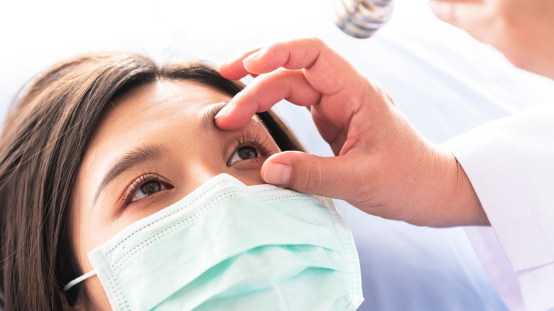 Doctor opening patient eyelid