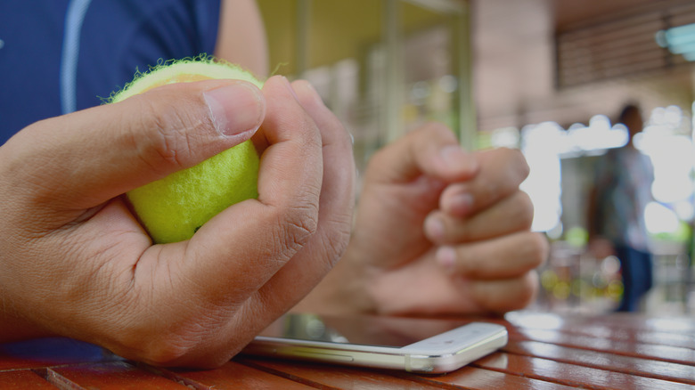 hand squeezing a tennis ball