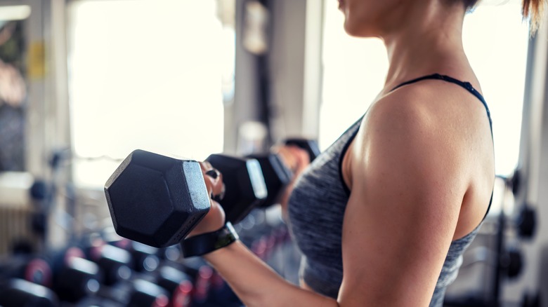 woman curling dumbbells at a gym