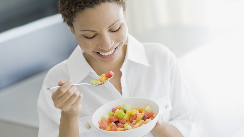 woman eating a bowl of fruit for breakfast