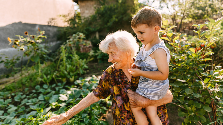 older woman holding her grandson in a garden