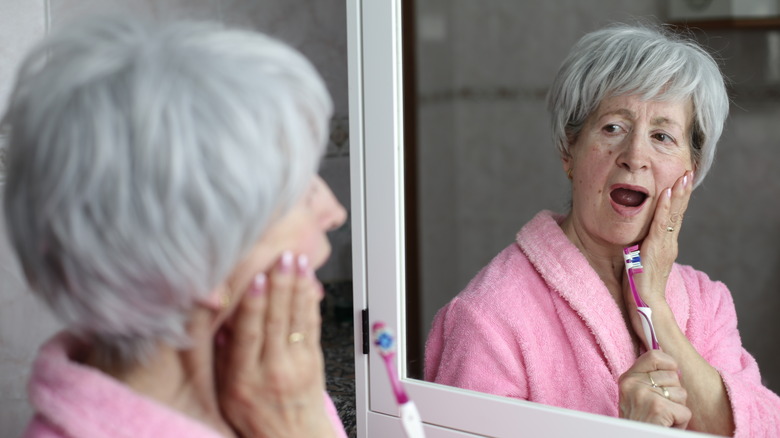 woman doing jaw exercises in the mirror