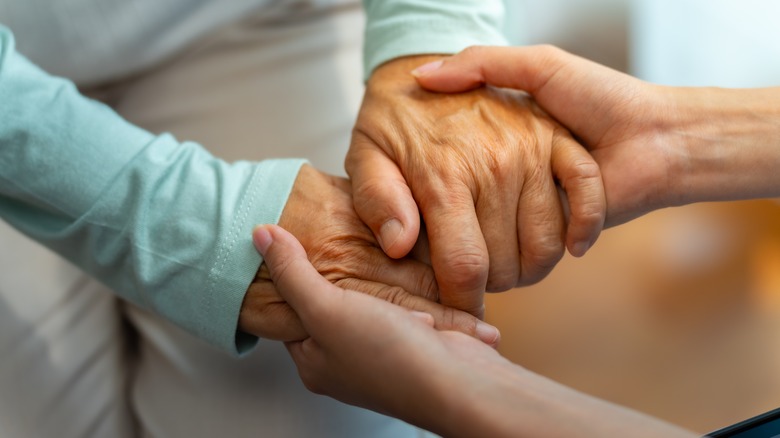 one person holding hands with elderly person