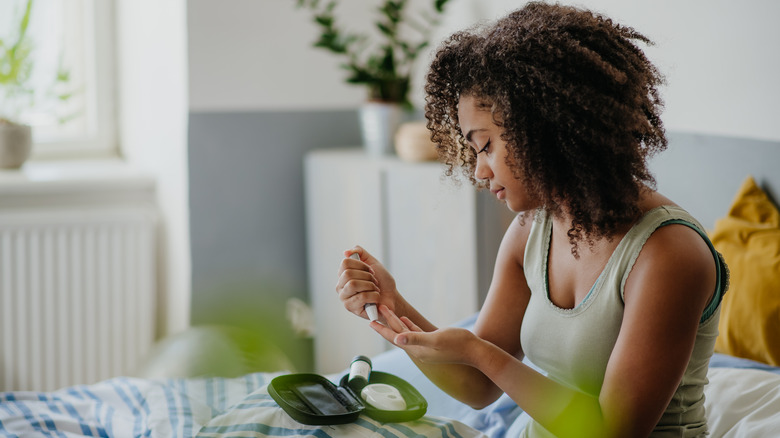 young woman testing glucose levels to manage diabetes