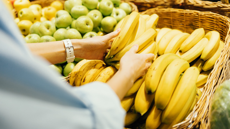 woman grabbing bananas at grocery store