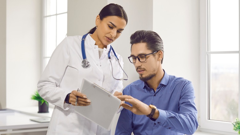 man and his doctor looking at doctor's clipboard