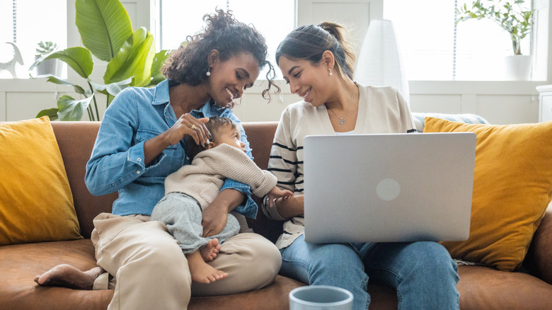 Smiling couple holding baby on couch