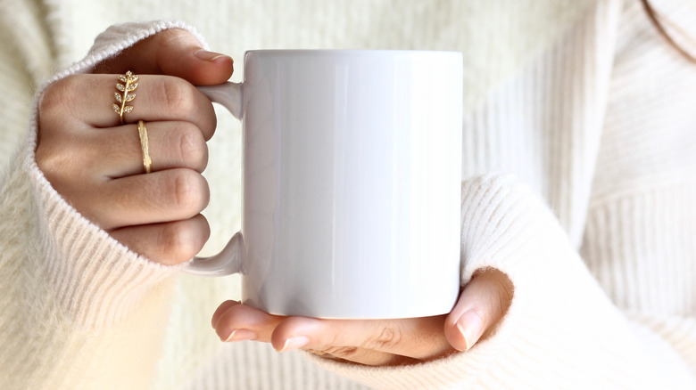 Woman in white sweater holding mug