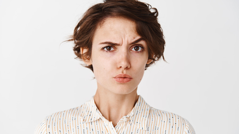 Woman appearing skeptical with white background