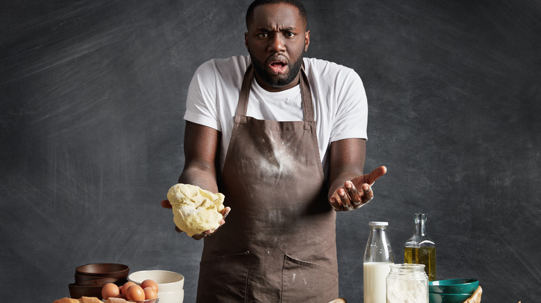 A man trying to cook, looking confused