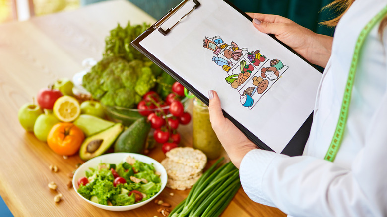 Woman holding a clipboard with food on it, in front of food