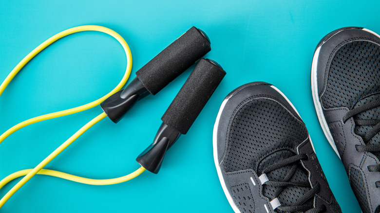 yellow jumprope and black athletic shoes on blue background