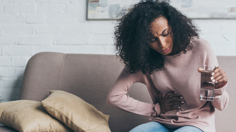 Woman on the couch clutching her stomach