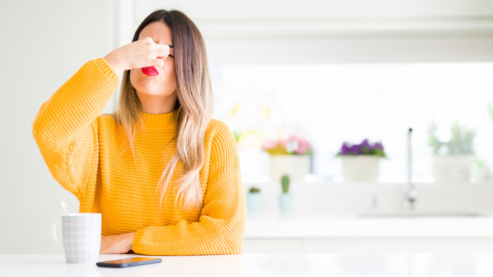 Woman holding her nose, about to drink something