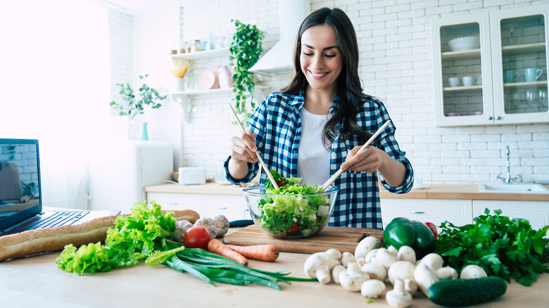 A woman makes a salad in the kitchen