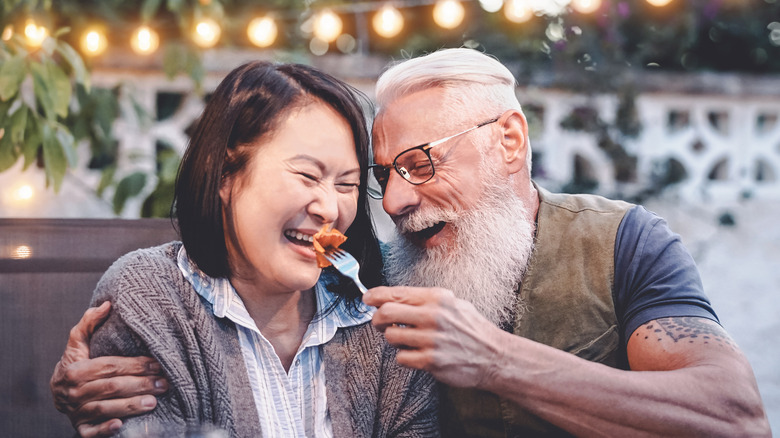 Two older adults laughing at the dinner table