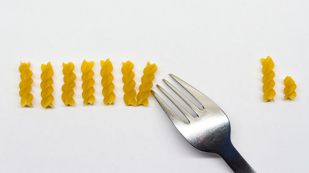 Pieces of pasta being counted with a fork