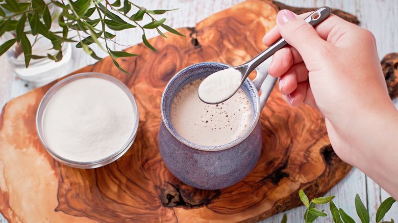 spooning collagen powder into hot cocoa