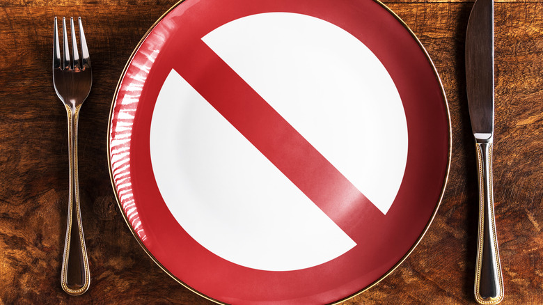 A fork and knife next to a plate with a Do Not Enter sign on it