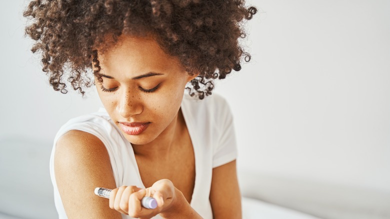 black woman injecting insulin in her arm