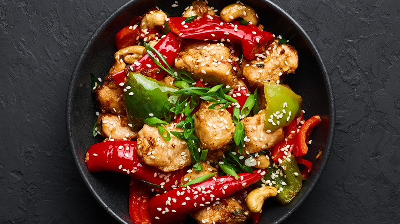 Szechuan chicken with peppers in a black bowl 