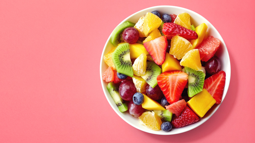 A bowl of fruit on a pink background