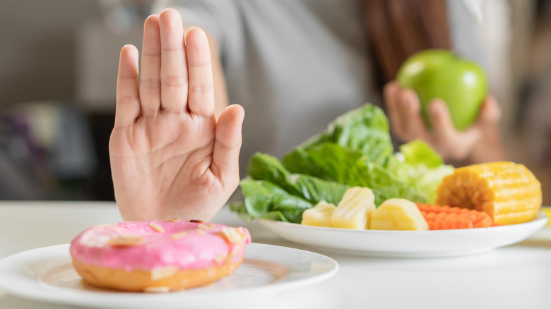 woman denying a donut choosing vegetables