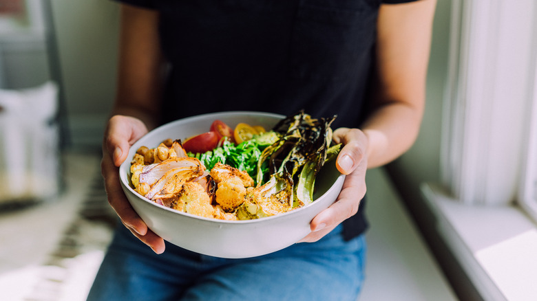 woman holding a plate of roasted vegetables