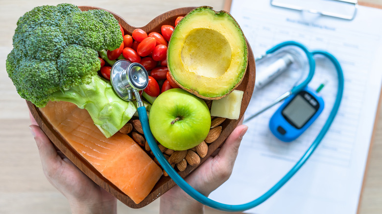 heart-shaped bowl with healthy food and stethoscope