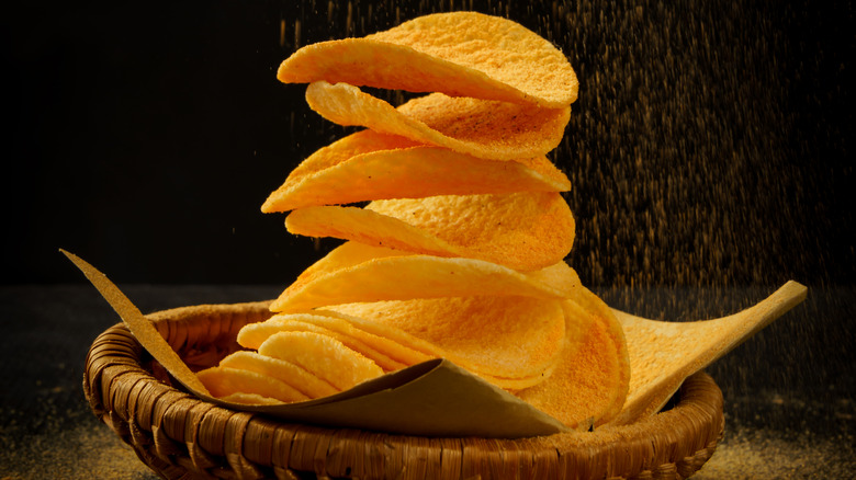 close up of a stack of potato chips with powder cheese falling