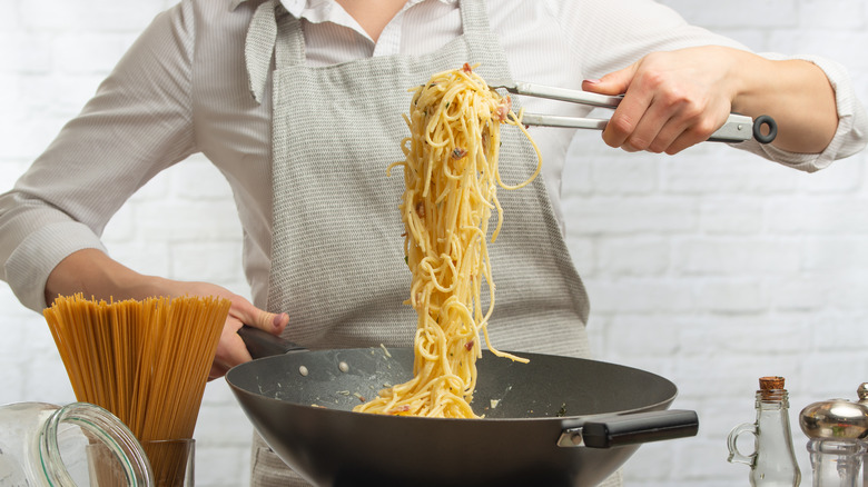 Man cooks spaghetti in a wok