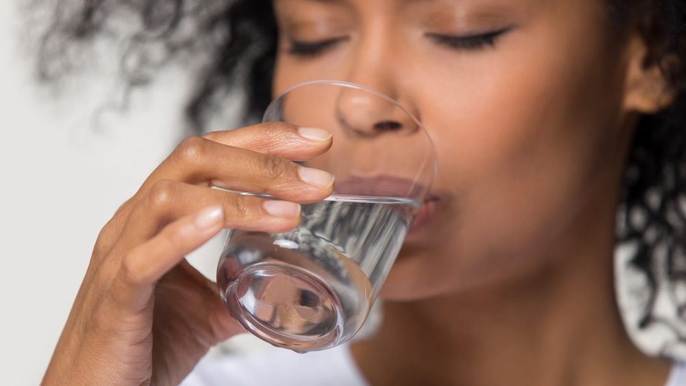 close up of a young woman drinking a glass of water 