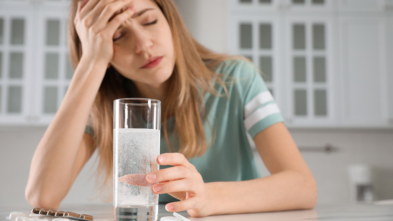 woman taking meds and water post-hangover