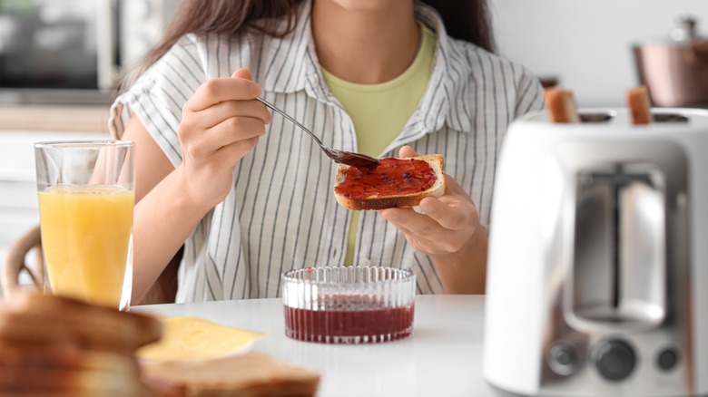 Woman's hands spreading jam on toast