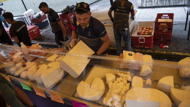Worker with blocks of cheese at stall