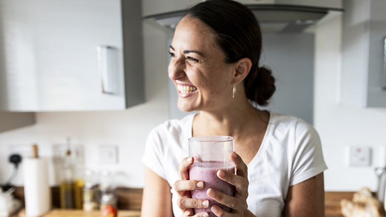 woman holding a glass of berry smoothie