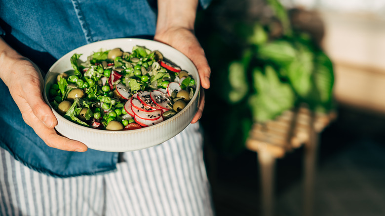 woman holding bowl of vegetables and beans