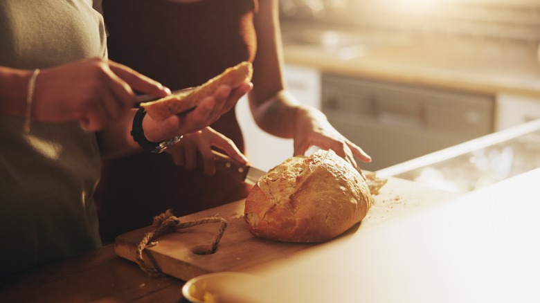 couple cutting and preparing fresh bread