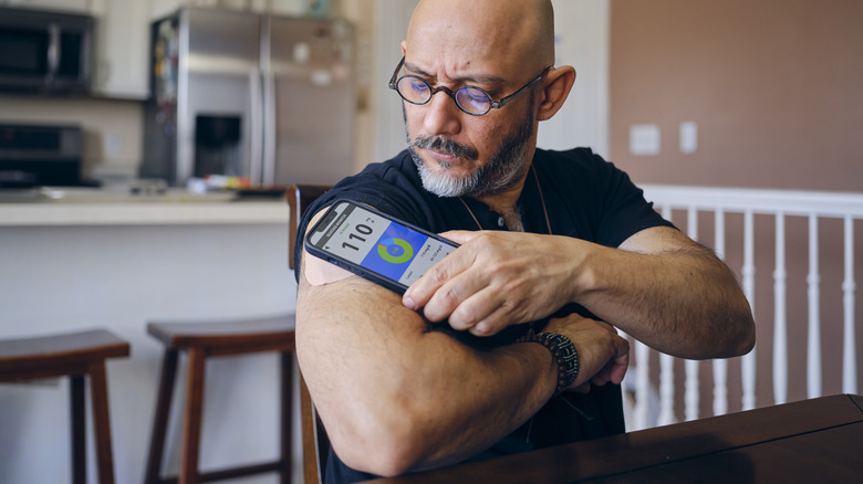 man checking blood sugar in kitchen