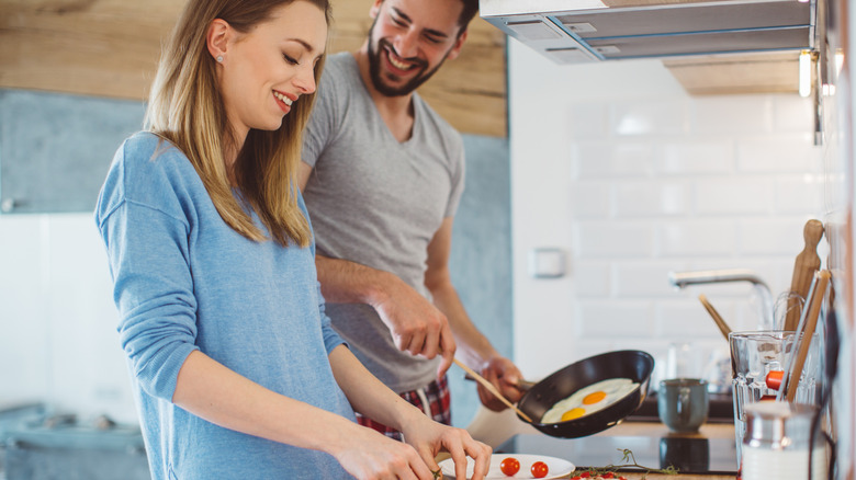 woman and man couple making egg breakfast