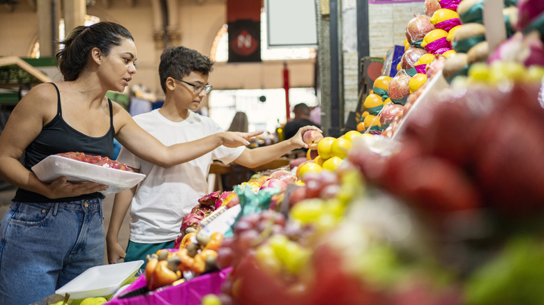 A woman and her son shop for fruits and vegetables